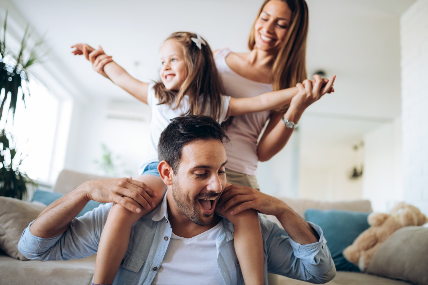 Mom and Dad playing with their daughter on the Dads shoulders